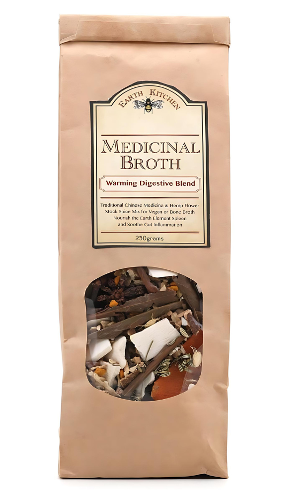 Earth Kitchen Medicinal Broth Warming Digestive Blend packaging, featuring traditional Chinese medicine and hemp flower. The bag is tan with a clear window displaying a mix of herbs, roots, and spices for making broth, labeled for 250 grams.